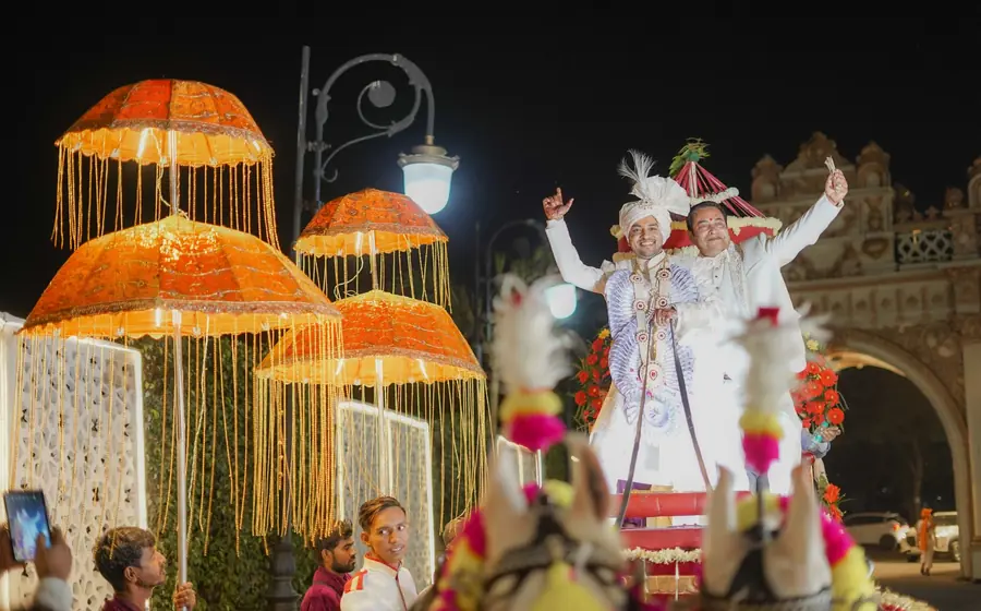 Groom on a decorated horse in a night baraat procession outside a palace