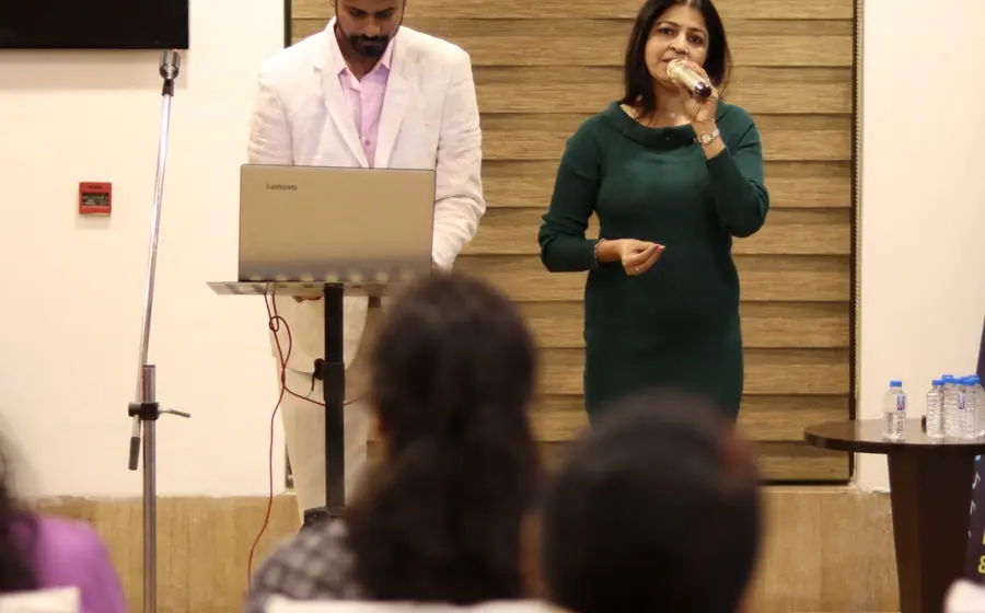 Speaker with a microphone presenting to a seated audience