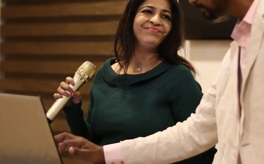 Presenter holding a microphone next to a laptop