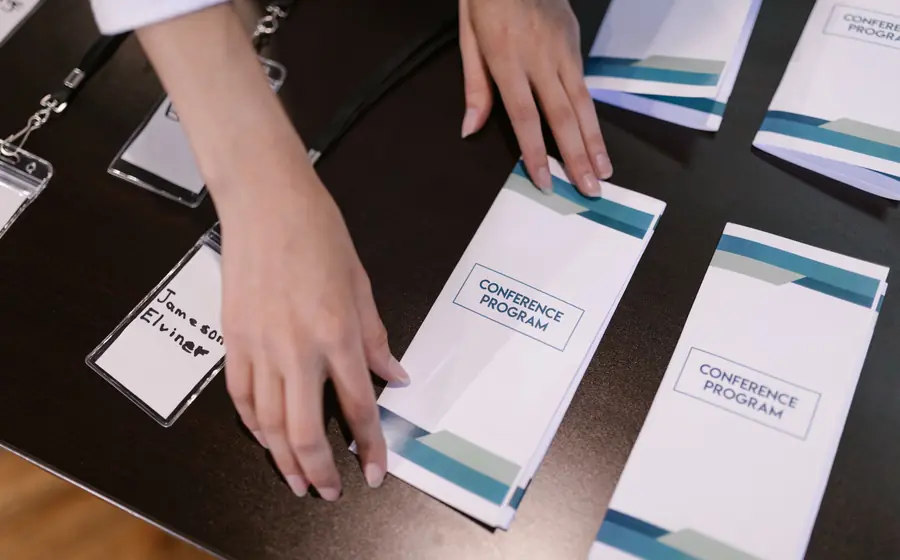 Conference programmes and name badges laid out on a registration desk