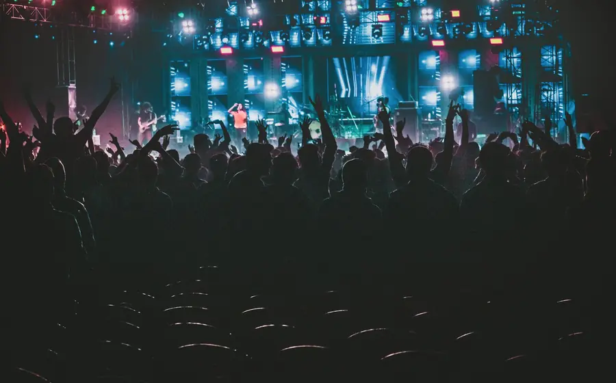 Party crowd with hands up in front of stage lights