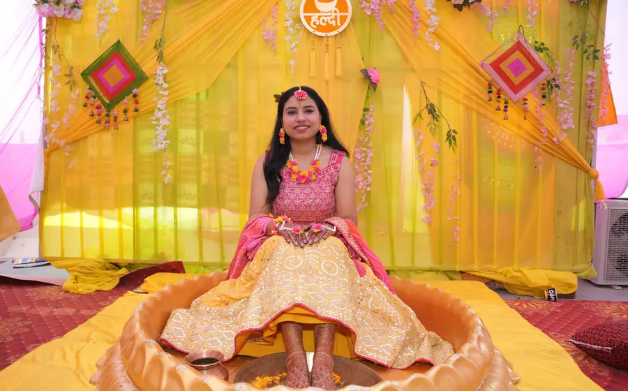 Bride sitting in a yellow decorated haldi mandap