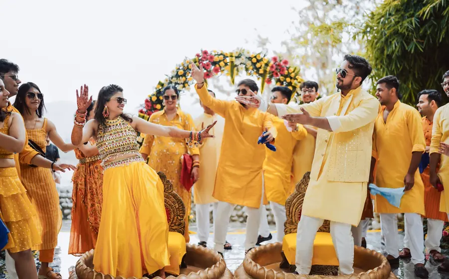 Family and friends in yellow dancing together at a sangeet