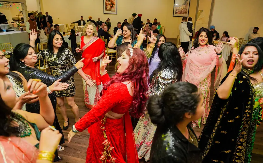 Women in colourful outfits dancing at a sangeet