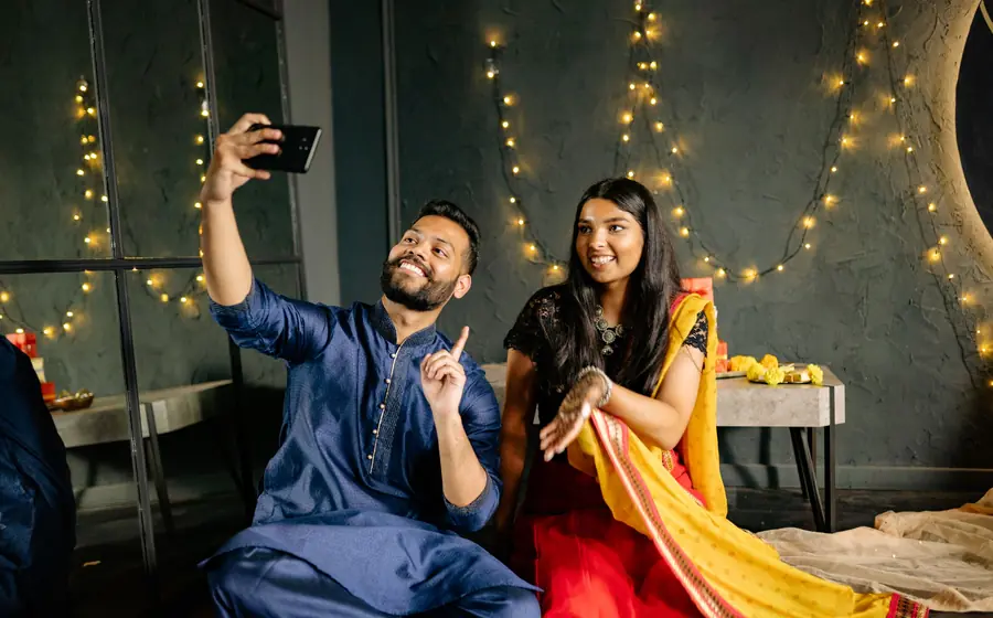 Two friends taking a selfie under string lights