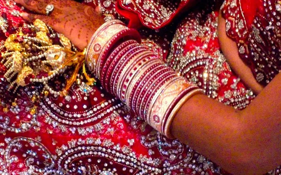 Close-up of a bride's red wedding bangles and embroidered outfit