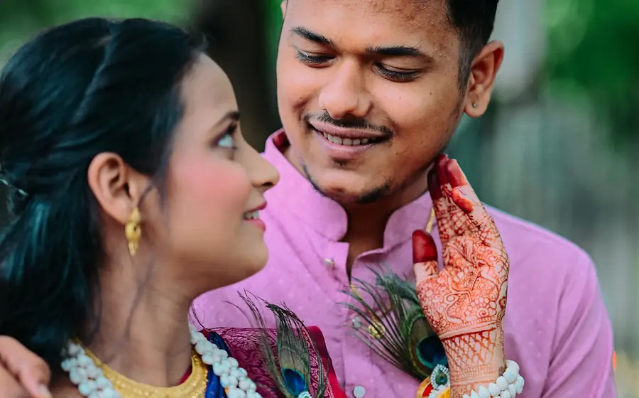 Couple smiling at each other, the bride with henna on her hands